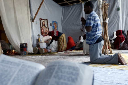 Christian migrants from Eritrea and Ethiopia pary and read the bible before Sunday mass at the makeshift church in 'The New Jungle' near Calais, France, August 2, 2015. 