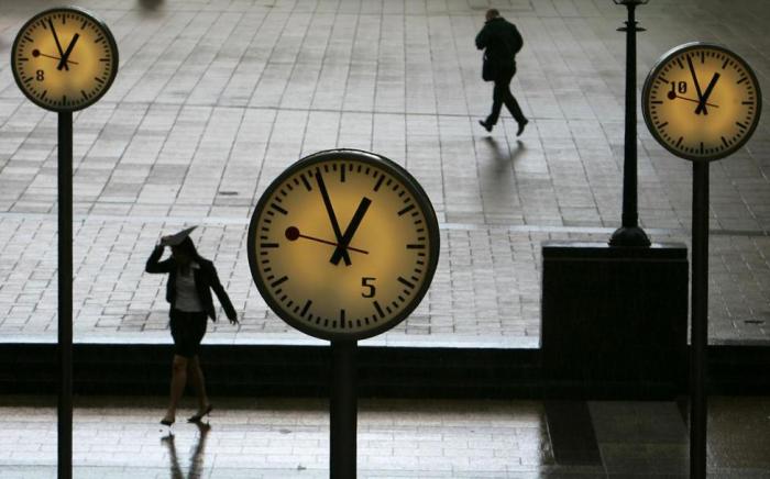 Workers shelter from the rain at Reuters Plaza in Canary Wharf, Docklands, east London May 10, 2005.