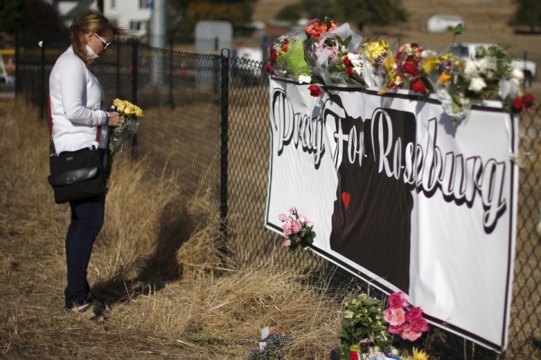 Leanne DiLorenzo, 48, leaves flowers at a memorial outside Umpqua Community College in Roseburg, Oregon, United States, October 3, 2015. The gunman who killed his English professor and eight others at an Oregon community college committed suicide after a shootout with police who were on the scene within five minutes and exchanged fire with him almost immediately, authorities said.