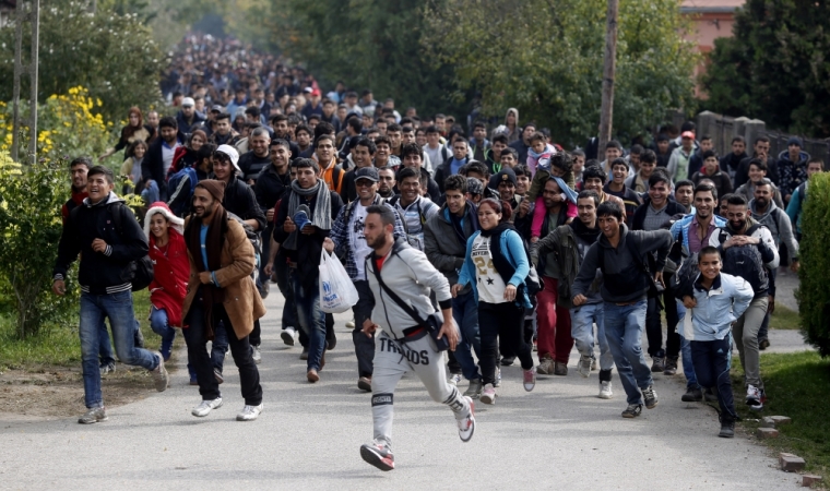 Migrants run toward the Austrian border from Hegyeshalom, Hungary, October 6, 2015. Austria and Germany have committed to backing Greek efforts to secure more EU funds to cope with the influx and to boost staff on the ground. Many of the almost 400,000 migrants who have arrived in Greece this year have later passed through Austria on their way to Germany.