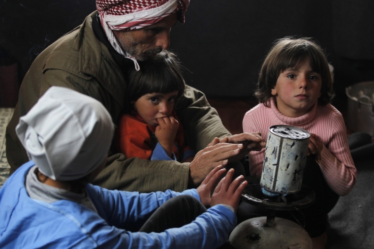 A Syrian refugee family warm up at their caravan after heavy rain at the Al Zaatari refugee camp in the Jordanian city of Mafraq, near the border with Syria, December 12, 2013. Weather conditions in the Al Zaatari refugee camp north of Jordan worsened as the country faced winter storms on Thursday. Many tents were flooded and several others were damaged by strong winds and the heavy rains in the camp which is home to 120,000 Syrians who have fled the conflict in their home country.