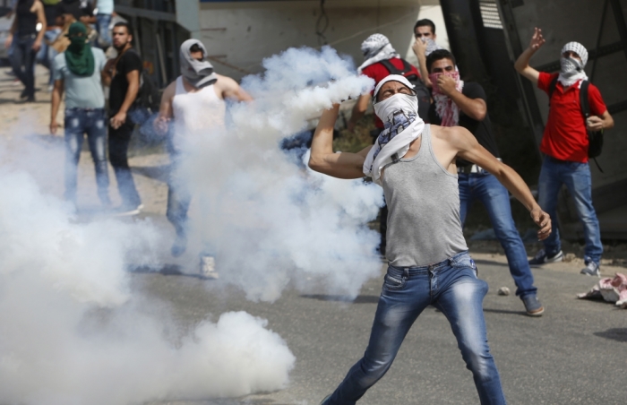 A masked Palestinian protester hurls back a tear gas canister fired by Israeli troops during clashes in the West Bank city of Hebron October 18, 2015. Forty-one Palestinians and seven Israelis have died in recent street violence, which was in part triggered by Palestinians' anger over what they see as increased Jewish encroachment on Jerusalem's al-Aqsa mosque compound.