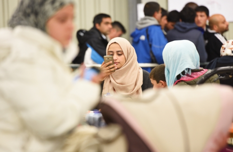 A migrant uses her cell phone in a canteen in a refugee camp in Celle, Lower-Saxony, Germany, October 15, 2015. With the approach of winter, authorities are scrambling to find warm places to stay for the thousands of refugees streaming into Germany every day. In desperation, they have turned to sports halls, youth hostels and empty office buildings. But as these options dry up, tent cities have become the fall-back plan: despite falling temperatures, a survey by German newspaper Die Welt showed at least 42,000 refugees were still living in tents.