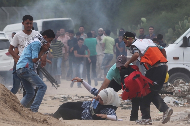 A female journalist lies on the ground after inhaling gas fired by Israeli troops during clashes with protesters near border between Israel and Central Gaza Strip, October 23, 2015. Palestinian factions called for mass rallies against Israel in the occupied West Bank and East Jerusalem in a 'day of rage' on Friday, as world and regional powers pressed on with talks to try to end more than three weeks of bloodshed.