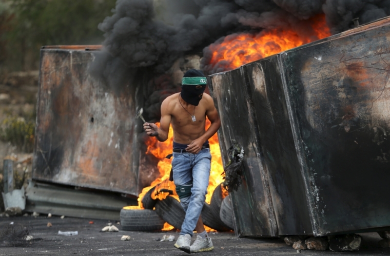 A Palestinian protester takes cover during clashes with Israeli troops near the Jewish settlement of Bet El, near the West Bank city of Ramallah, October 23, 2015. Palestinian factions called for mass rallies against Israel in the occupied West Bank and East Jerusalem in a 'day of rage' on Friday, as world and regional powers pressed on with talks to try to end more than three weeks of bloodshed.