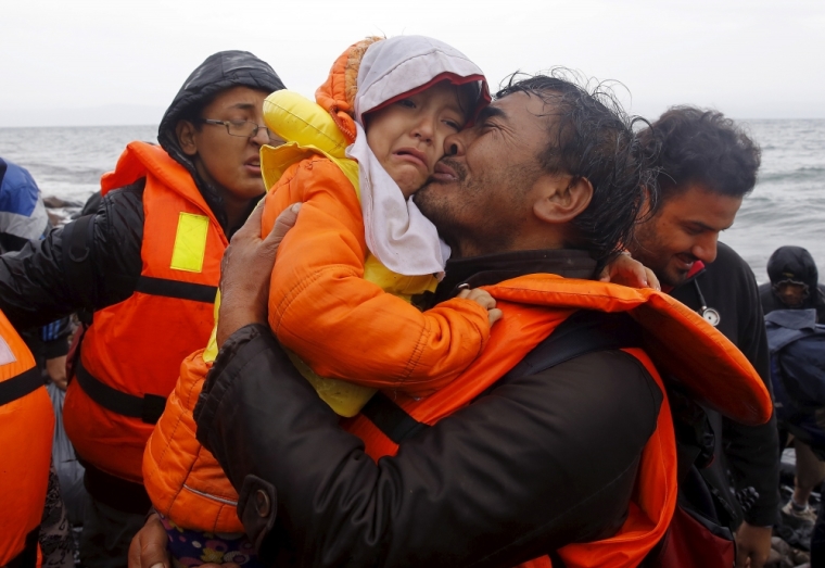 An Afghan migrant kisses his child moments after disembarking from a raft at a rocky beach during a rainstorm on the Greek island of Lesbos, October 24, 2015. Over half a million refugees and migrants have arrived by sea in Greece this year and the rate of arrivals is rising, in a rush to beat the onset of freezing winter, the United Nations said.