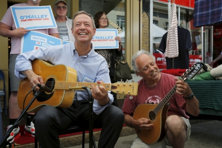 An unidentified man plays a guitar with Paul Delnero (R) outside the Celtic Crossing shop during Market Square Day in Portsmouth, New Hampshire, June 13, 2015.