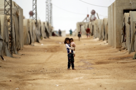 A girl holds a child inside a refugee camp for the internally displaced in Jrzinaz area, southern part of Idlib province, Syria October 13, 2015.