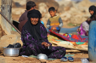 An internally displaced woman sits with others outside their tents at a makeshift refugee camp in Sinjar town, in Idlib province, Syria November 20, 2015.