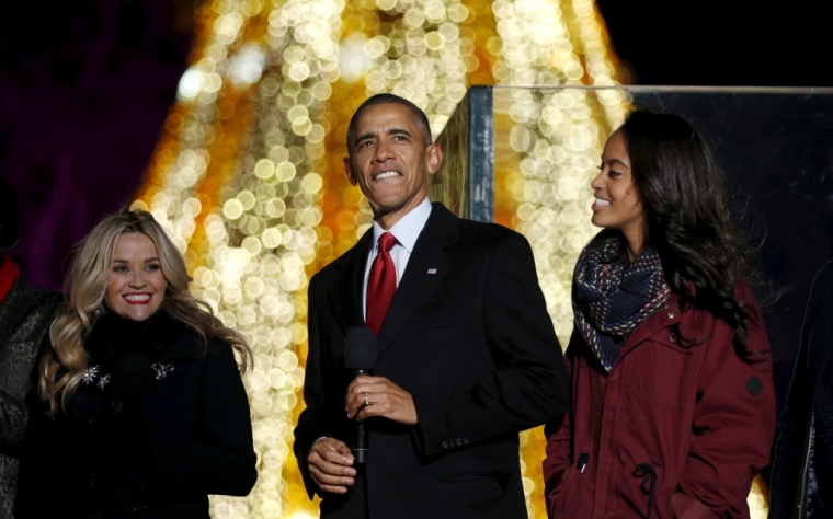 U.S. President Barack Obama, flanked by actress Reese Witherspoon and daughter Malia, sings onstage during the National Christmas Tree Lighting and Pageant of Peace ceremony on the Ellipse Washington December 3, 2015.