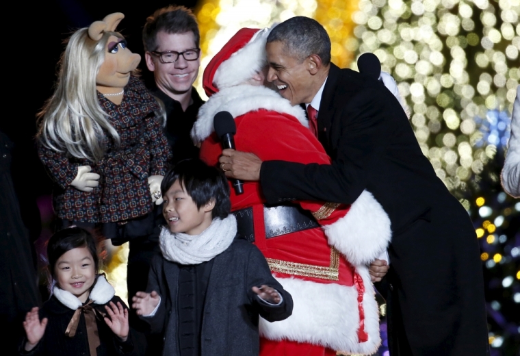 U.S. President Barack Obama hugs a man dressed as Santa Claus as Muppets character Miss Piggy (top L) watches during the National Christmas Tree Lighting and Pageant of Peace ceremony on the Ellipse near the White House in Washington December 3, 2015.