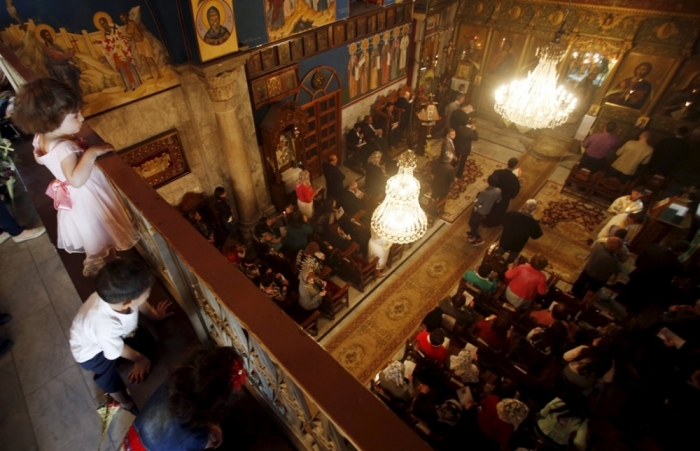 Palestinian children watch worshippers as they attend Orthodox Christian Palm Sunday mass at the Saint Porfirios church in Gaza City April 5, 2015.