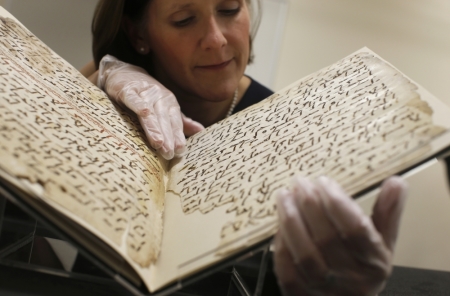 Conservator, Marie Sviergula holds a fragment of a Quran manuscript in the library at the University of Birmingham in Britain, July 22, 2015. A British university said on Wednesday that fragments of a Quran manuscript found in its library were from one of the oldest surviving copies of the Islamic text in the world, possibly written by someone who might have known the Islamic prophet Muhammad. Radiocarbon dating indicated that the parchment folios held by the University of Birmingham in central England were at least 1,370 years old, which would make them one of the earliest written forms of the Islamic holy book in existence.