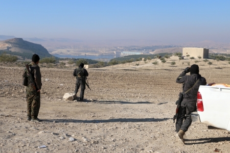 Kurdish fighters from the People's Protection Units, who are fighting alongside with the Democratic Forces of Syria, stand near the Tishrin dam, after they captured it on Saturday from Islamic State militants, south of Kobani, Syria, December 27, 2015. A U.S.-backed alliance of Syrian Kurds and Arab rebel groups, supported by U.S. coalition planes, captured a dam on Saturday from Islamic State, cutting one of its main supply routes across the Euphrates, an alliance spokesman said.