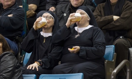 Two women wearing nun outfits drink beer while watching the playoff draw between Quebec and Manitoba at the 2014 Tim Hortons Brier curling championships in Kamloops, British Columbia, March 8, 2014.