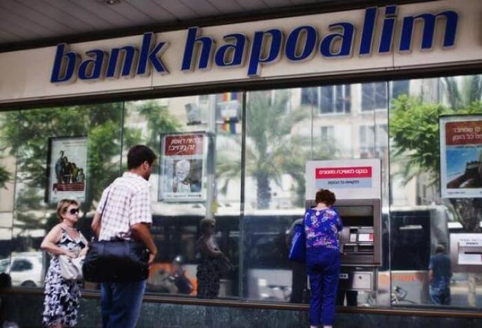 A woman uses an automated teller machine (ATM) outside a Bank Hapoalim branch in Tel Aviv May 30, 2013.