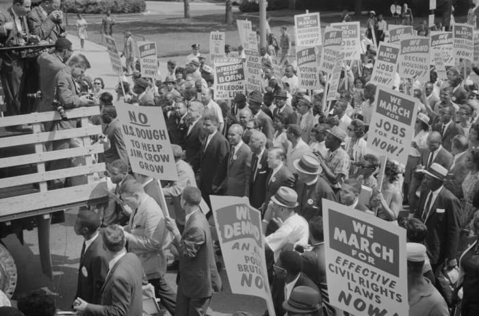 Civil rights leaders, including Martin Luther King, Jr., surrounded by crowds carrying signs, during the civil rights march on Washington D.C., in this August 28, 1963 photograph courtesy of the Library of Congress.