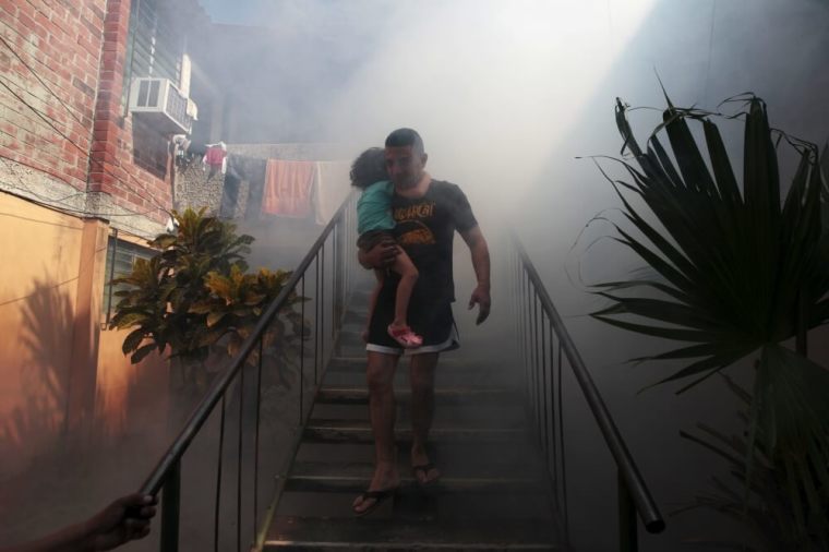 A man walks away from his home with his son as health workers fumigates the Altos del Cerro neighbourhood as part of preventive measures against the Zika virus and other mosquito-borne diseases in Soyapango, El Salvador, January 21, 2016.