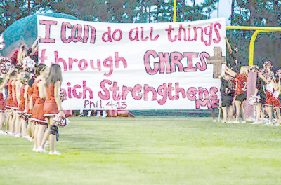 Kountze, Texas cheerleaders holding banner with Bible verse.