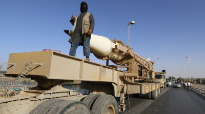 A militant Islamist fighter gestures as he takes part in a military parade along the streets of Syria's northern Raqqa province on June 30, 2014.