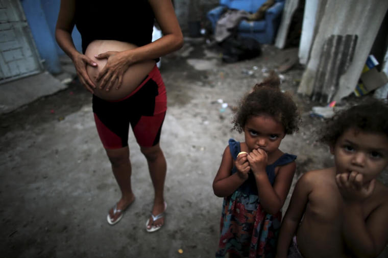 Patricia Araujo (L), 23, who is seven-months pregnant, stands next to children as they pose in front of their stilt house, a lake dwelling also known as palafitte or 'Palafito,' in Recife, Brazil, February 8, 2016. The Zika virus may be particularly adept at entrenching itself in parts of the body that are shielded from the immune system, making it harder to fight off and possibly lengthening the timeframe in which it can be transmitted, top U.S. experts said on Friday. Picture taken February 8, 2016.