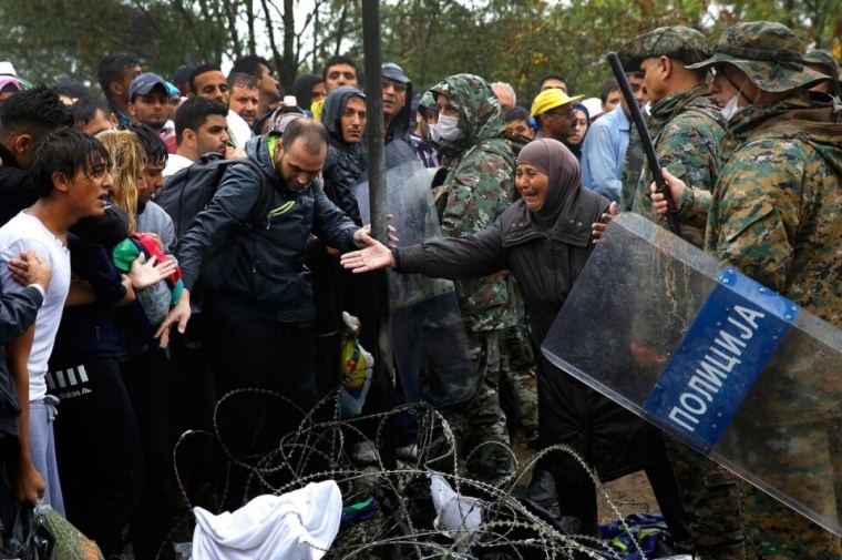 A Syrian woman begs a Macedonian soldier to allow members of her family to cross, September 10, 2015.