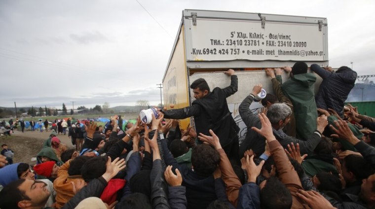 Migrants try to get products from a truck at a makeshift camp on the Greek-Macedonian border near the village of Idomeni, Greece, March 10, 2016.