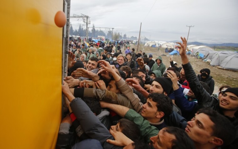 Migrants try to get products from a truck at a makeshift camp on the Greek-Macedonian border near the village of Idomeni, Greece, March 10, 2016.