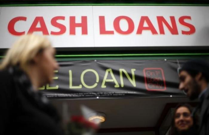 Pedestrians pass by a lending shop in northeast London October 3, 2013.