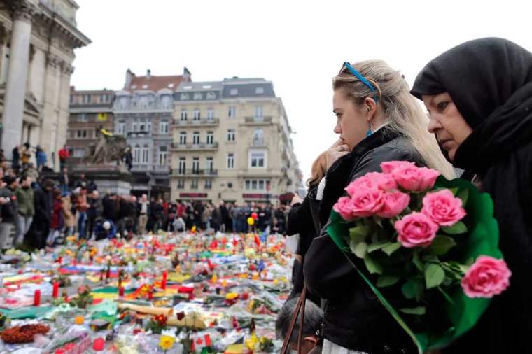 People observe a minute of silence at a street memorial to victims of Tuesdays's bombings in Brussels, Belgium, March 24, 2016.