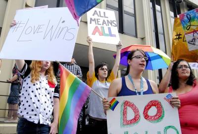 Demonstrators stand on the front steps of the federal building waving a rainbow flag in Ashland, Kentucky, September 3, 2015.