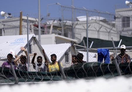 Migrants and refugees stand behind a fence as Pope Francis visits at the Moria refugee camp near the port of Mytilene, on the Greek island of Lesbos, Greece, April 16, 2016.