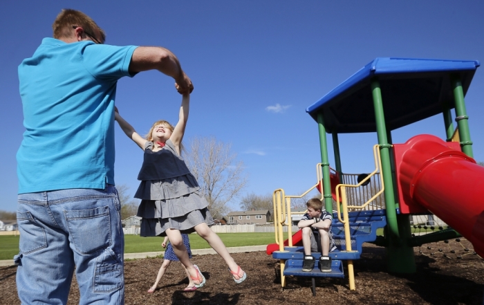 Joe Smith plays with his daughter Norah as his son Chase looks on at a playground in Winthrop Harbor, Illinois, May 9, 2014. Picture taken May 9, 2014.