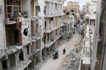 Residents walk near damaged buildings in the rebel held area of Old Aleppo, Syria May 5, 2016.