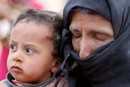 A Syrian refugee, who is stuck between the Jordanian and Syrian borders, cries and holds her child as she waits to cross into Jordan after a group of refugees had crossed into Jordanian territory, near the town of Ruwaished, at the Hadalat area, east of the capital Amman, May 4, 2016.