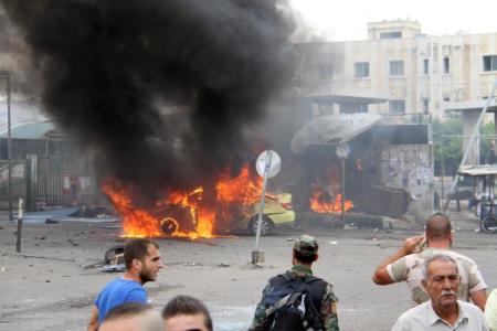 A Syrian army soldier and civilians inspect the damage after explosions hit the Syrian city of Tartous, in this handout picture provided by SANA on May 23, 2016.