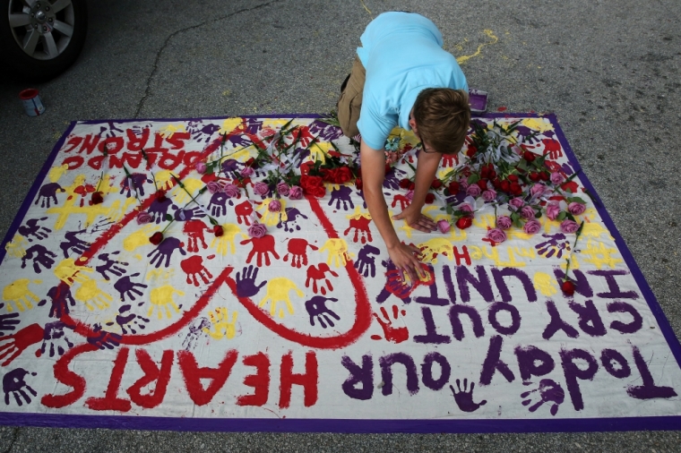 A man puts his hand print on a makeshift memorial on the ground near the Pulse gay nightclub where a mass shooting took place, in Orlando, Florida, U.S. June 12, 2016.