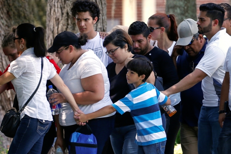 A boy creates a cordon around family members as they leave a senior citizen's center, after being notified about the fate of their loved ones, one day after a mass shooting at the Pulse gay night club in Orlando, Florida, U.S., June 13, 2016.