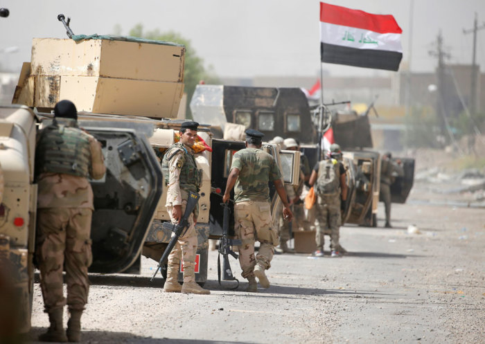 Iraqi army soldiers carry their weapons as they gather in the center of Falluja, Iraq, June 17, 2016.