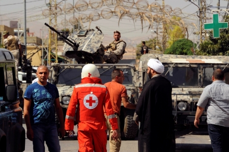 Lebanese army soldiers patrol as a Red Cross member walks near the site where suicide bomb attacks took place in the Christian village of Qaa, in the Bekaa valley, Lebanon, June 27, 2016.