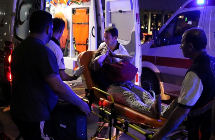 An injured woman covers her face as she is carried by paramedics into ambulance at Istanbul Ataturk airport, Turkey, following a blast June 28, 2016.