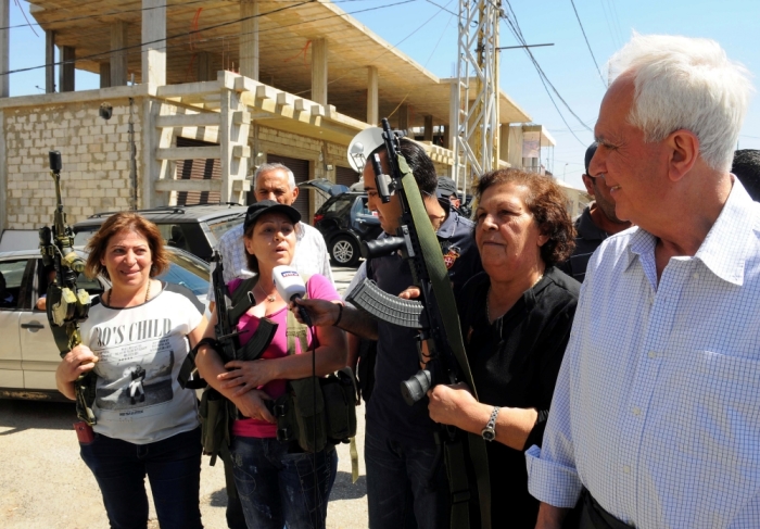 Member of the Syrian Social Nationalist Party and Lebanese MP Marwan Fares stands with women who are posing with guns and talking to journalists in the Christian village of Qaa, where suicide bomb attacks took place on Monday, in the Bekaa valley, Lebanon June 28, 2016.