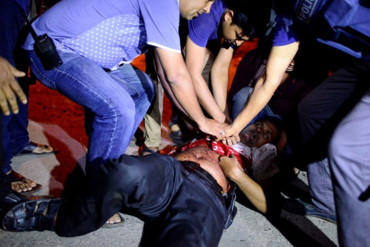 People try to help an injured person, after gunmen stormed the Holey Artisan restaurant and took hostages, in the Gulshan area of Dhaka, Bangladesh July 1, 2016.