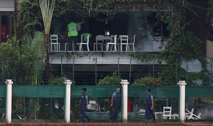 Policemen patrol outside the Holey Artisan Bakery and the O'Kitchen Restaurant as others inspect the site after gunmen attacked, in Dhaka, Bangladesh, July 3, 2016.