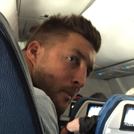 Tim Tebow prays with fellow-passengers as a man suffers a fatal heart attack on Delta Flight, June 2016.