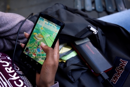 A woman uses a portable battery pack to charge her phone.