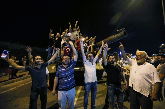 People stand on a Turkish army tank at Ataturk airport in Istanbul, Turkey July 16, 2016.