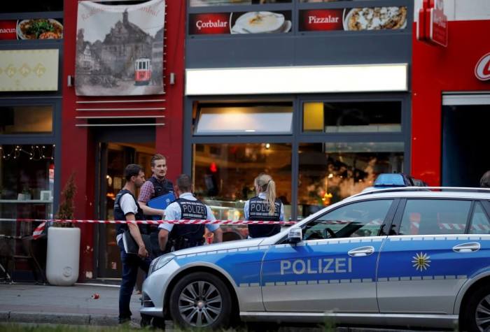 Police stand outside where a 21-year-old Syrian refugee killed a woman with a machete and injured two other people in the city of Reutlingen, Germany, July 24, 2016.