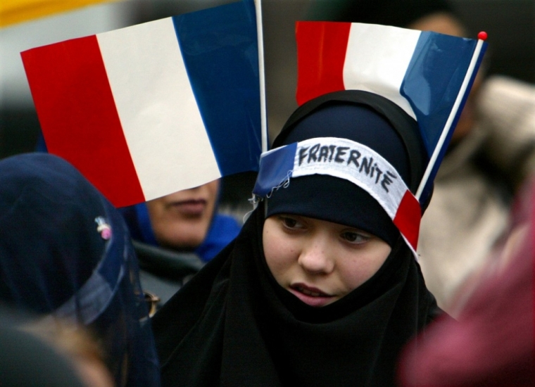 A young Muslim girl has two French flags and a headband reading “Fraternity” on her headscarf while marching to protest a French ban on religious symbols in state schools, Paris, January 31, 2004.