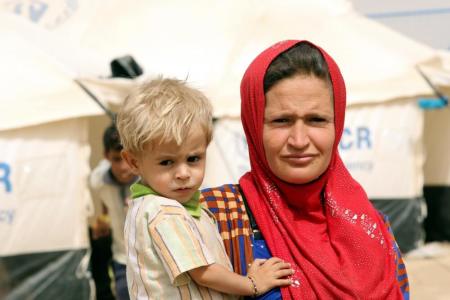 A displaced woman carries her child at a refugee camp in the Makhmour area near Mosul, Iraq, June 17, 2016. Picture taken June 17, 2016.